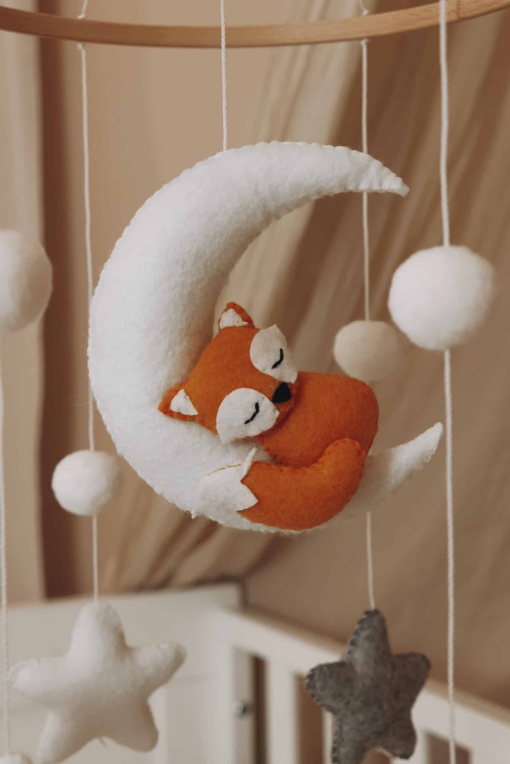 petit renard orange endormi sur une lune blanche en peluche