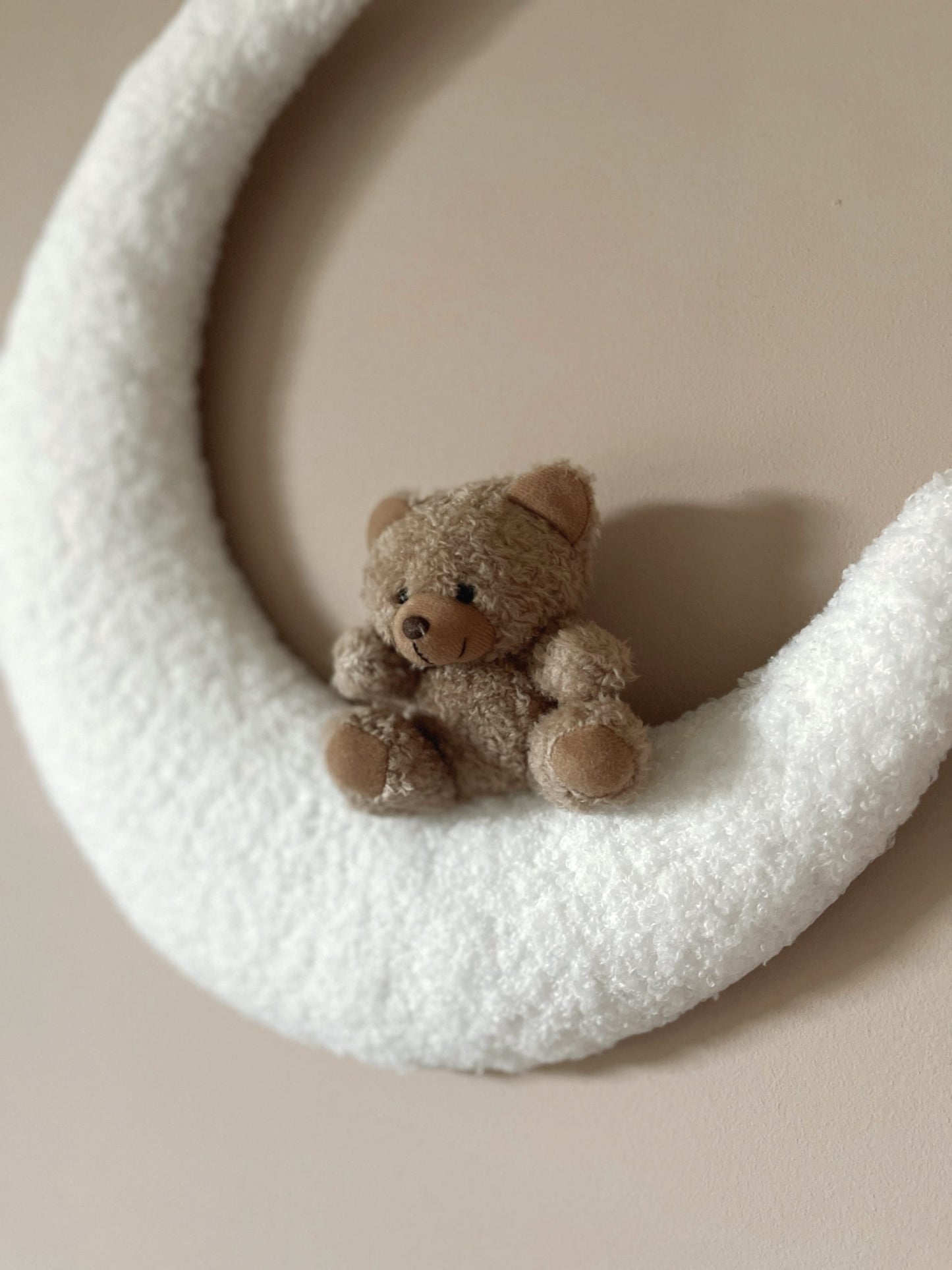 petit ourson brun assis sur une demi-lune blanche
