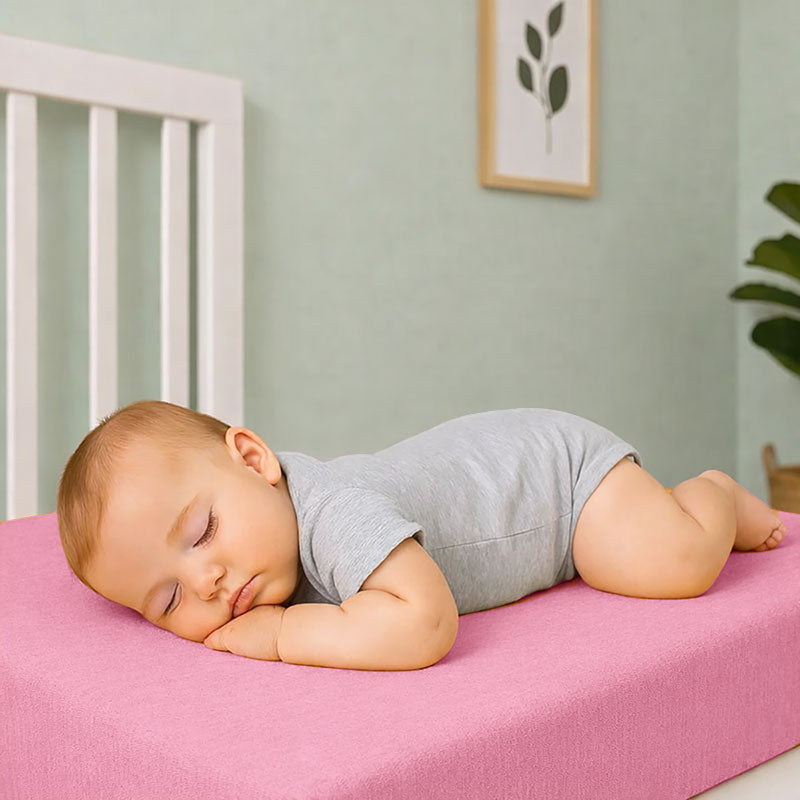Drap housse pour lit de bébé en double gaze de coton biologique rose, posé à plat et révélant sa texture gaufrée et douce. 60x120