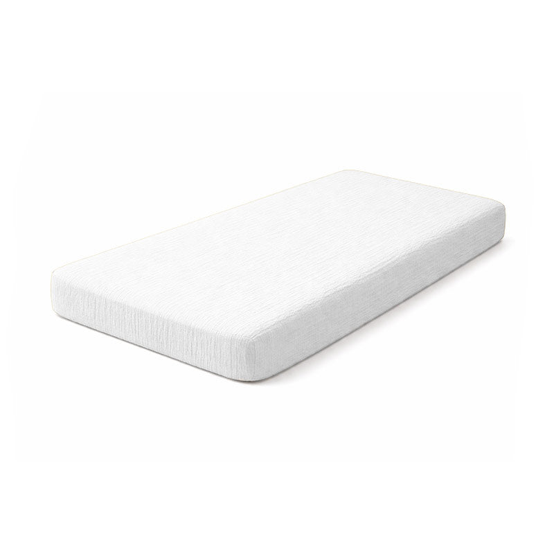 Drap housse pour lit de bébé en double gaze de coton biologique blanc, posé à plat et révélant sa texture gaufrée et douce. 60x120