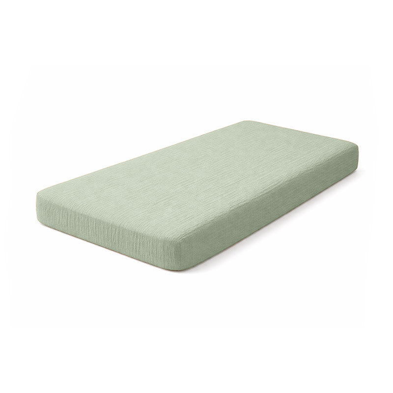 Drap housse pour lit de bébé en double gaze de coton biologique vert, posé à plat et révélant sa texture gaufrée et douce. 60x120