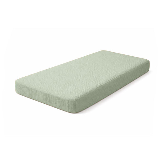 Drap housse pour lit de bébé en double gaze de coton biologique vert, posé à plat et révélant sa texture gaufrée et douce. 60x120