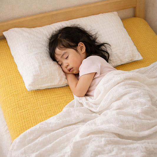 Drap housse pour lit de bébé en double gaze de coton biologique honey, posé à plat et révélant sa texture gaufrée et douce. 60x120
