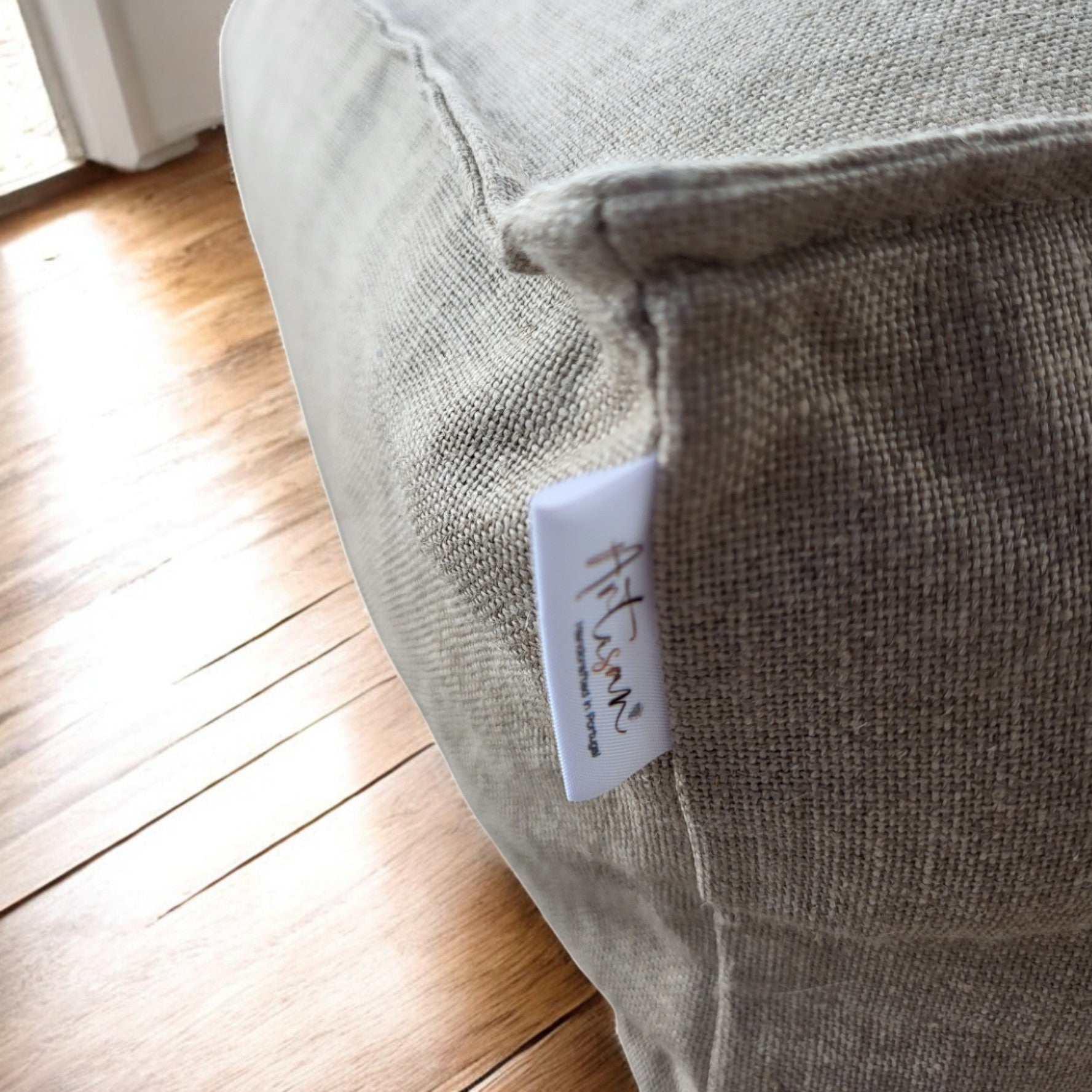 Grand coussin de sol carré de style zafu pour la méditation, en tissu de lin et coton de couleur beige naturel, posé dans un espace épuré.