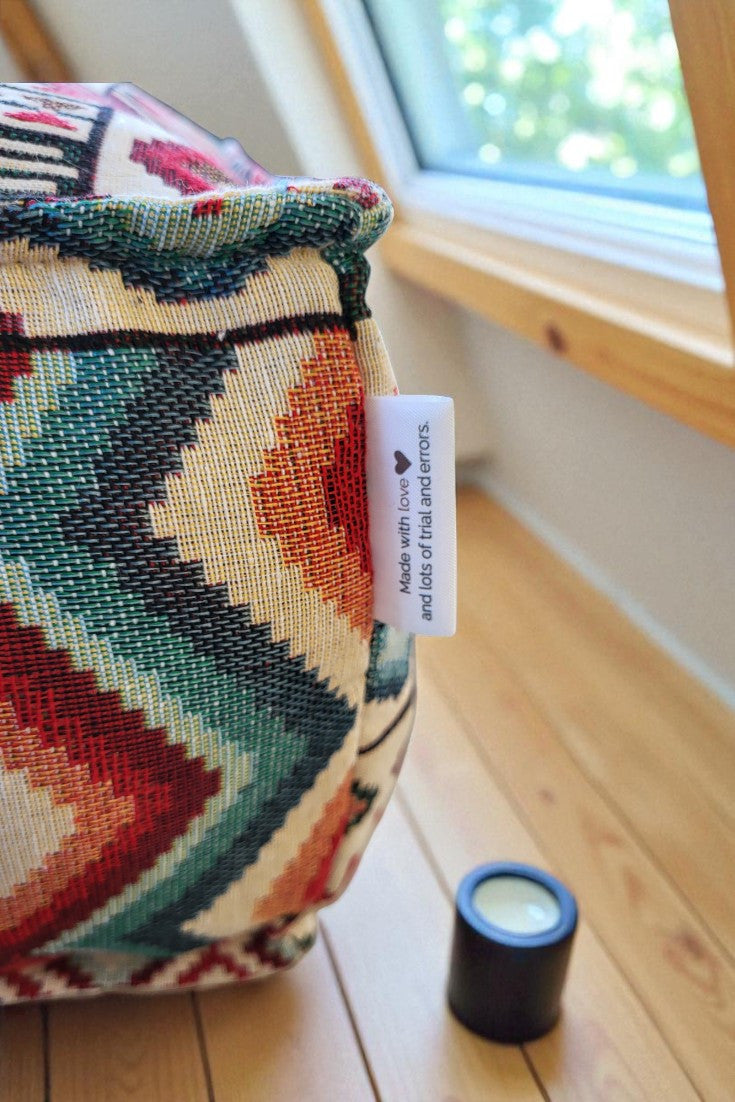 Grand coussin de sol zafu carré modèle Atlas, orné de motifs géométriques ethniques de style kilim aux couleurs rouge, bleu, orange et beige