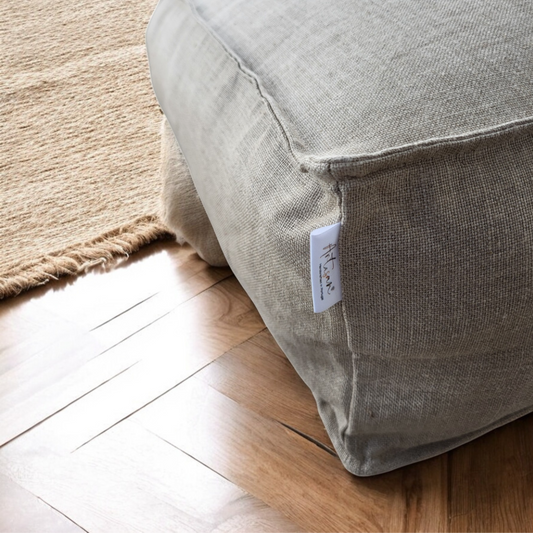 Grand coussin de sol carré de style zafu pour la méditation, en tissu de lin et coton de couleur beige naturel, posé dans un espace épuré.