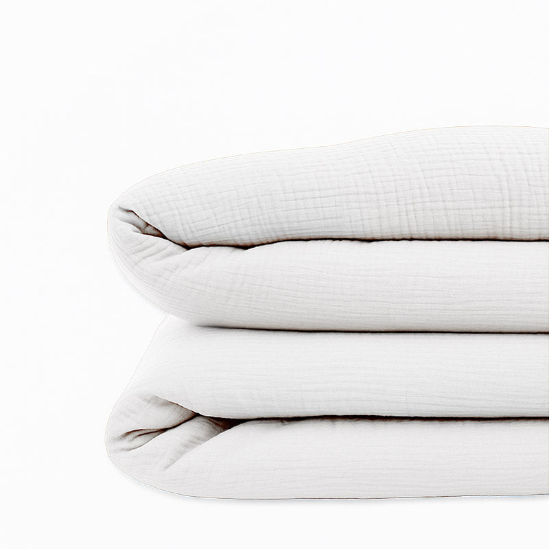Housse de couette pour lit d'enfant en coton biologique de couleur blanche, pliée de manière élégante.