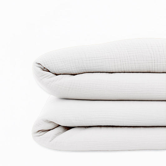 Housse de couette pour lit d'enfant en coton biologique de couleur blanche, pliée de manière élégante.
