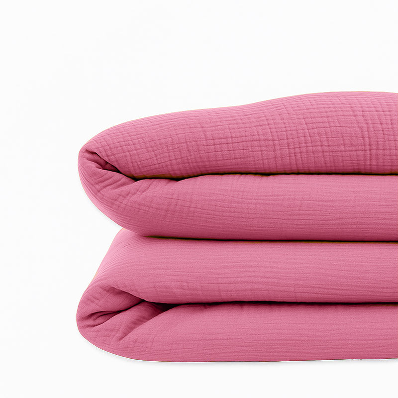 Housse de couette pour lit d'enfant en coton biologique de couleur rose, pliée de manière élégante. coton bio rose papate