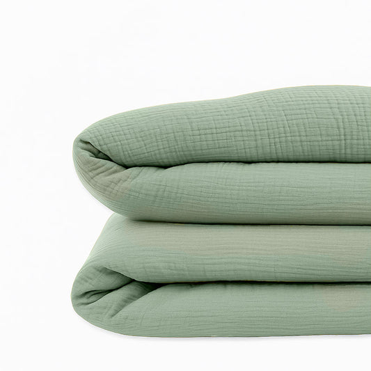 Housse de couette pour lit d'enfant en coton biologique de couleur vert sauge, pliée de manière élégante.