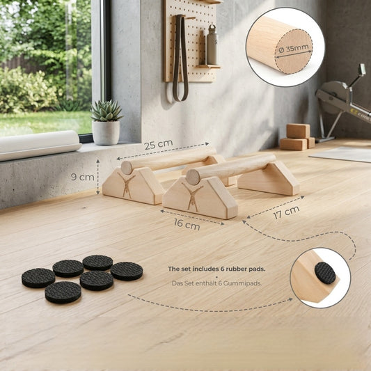 Photo de style de vie : Une paire de mini-paralllettes en bois Maxmoi avec toutes leurs dimensions (25cm, 16cm, 17cm, 9cm) dans une salle de gym à domicile lumineuse. Le set inclut 6 patins en caoutchouc.